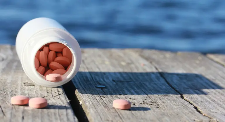 Bild av en burk med tabletter på en brygga. miljöproblem - läkemedel som kommer ut i vattnen. 